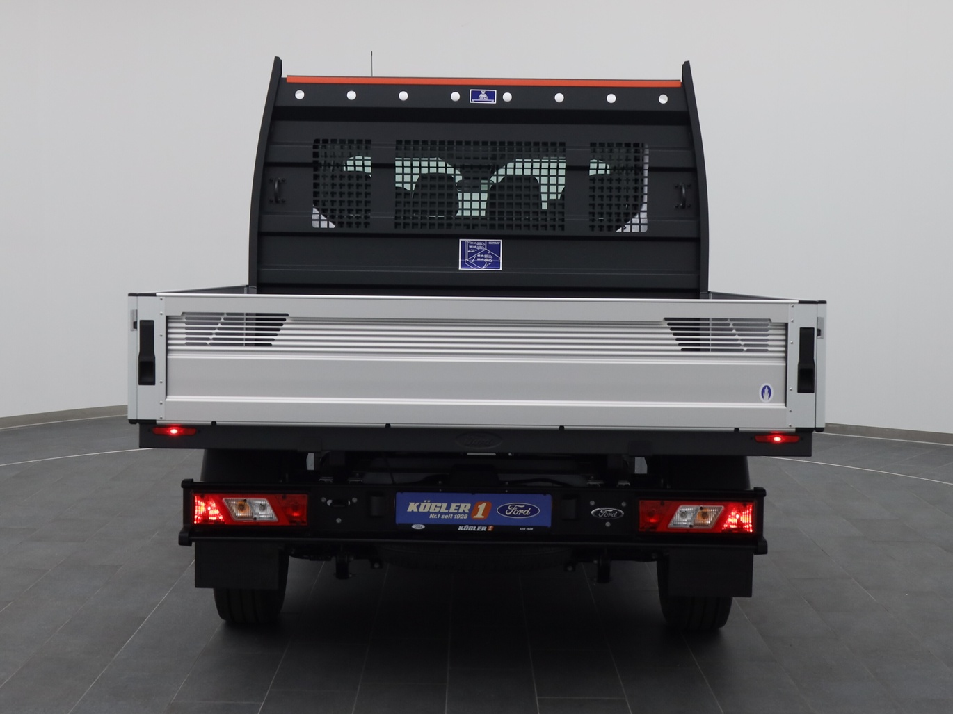 Heckansicht eines Ford Transit Pritsche DoKa 350 L2 Trail Hybrid in Weiss 