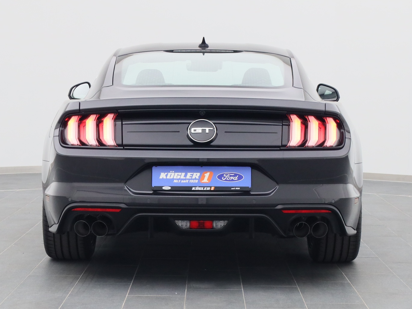 Heckansicht eines Ford Mustang GT Coupé V8 450PS / Premium 3 / B&O in Dark Matter Grey 