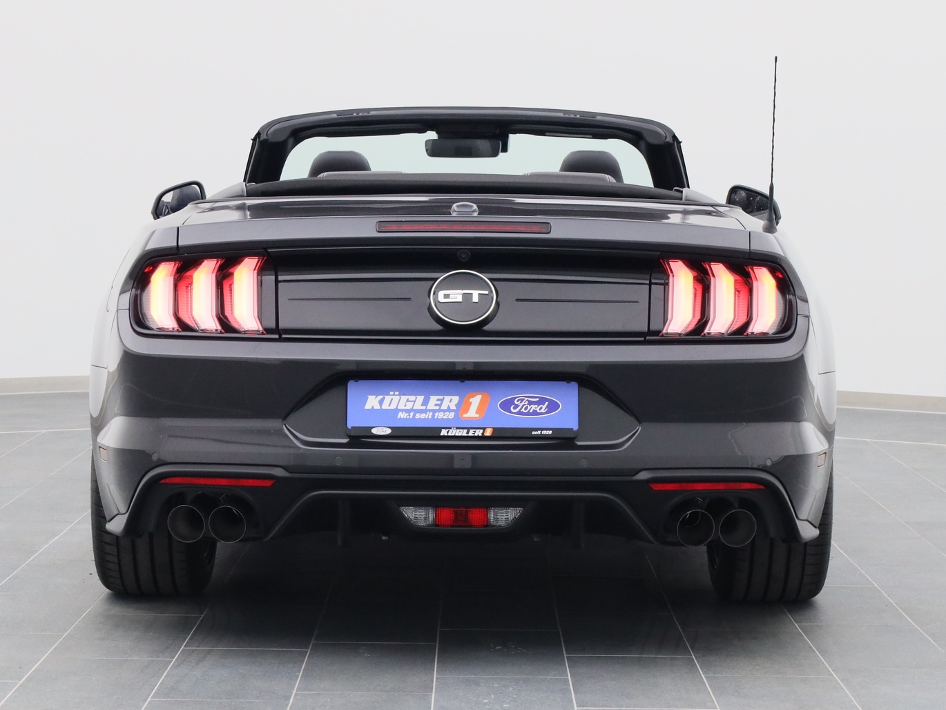 Heckansicht eines Ford Mustang GT Cabrio V8 450PS / Premium 4 / B&O in Dark Matter Grey 